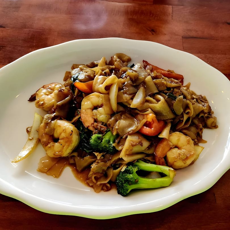Thai Origin Halal's Pad See Ew with shrimp, wide noodles, broccoli, and vegetables on a white plate.